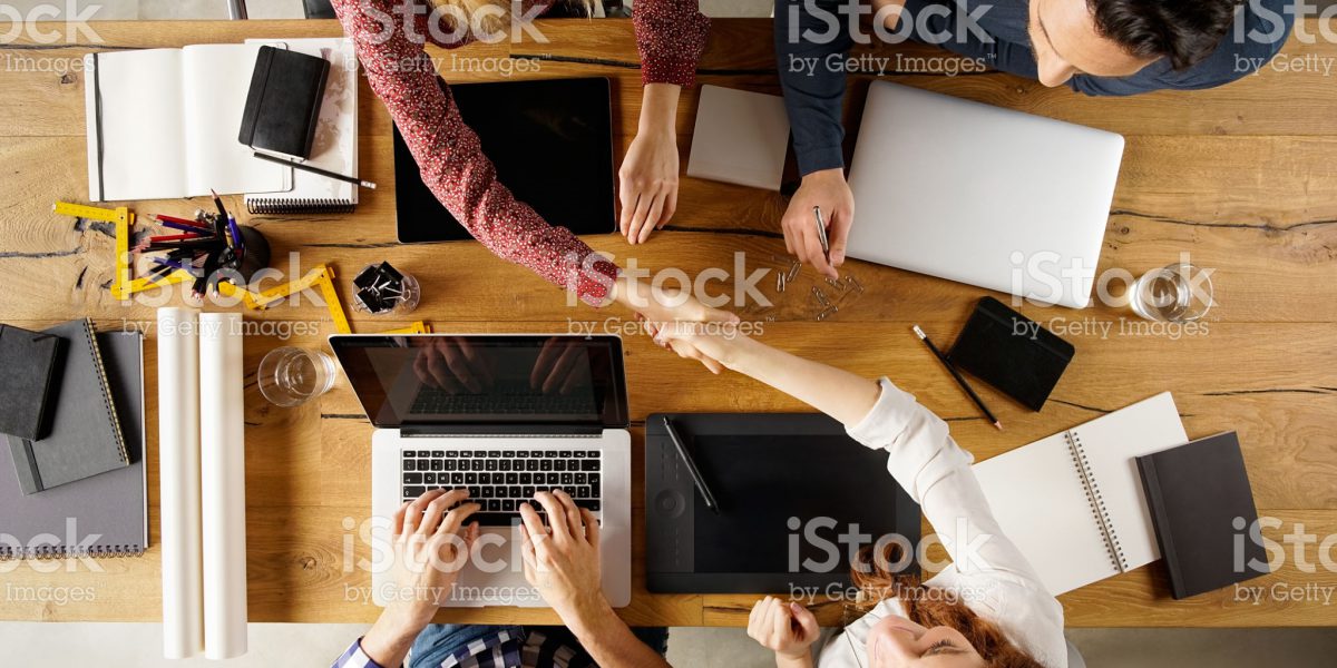 Top view of businesspeople shaking hands after sealing a deal. High angle view of casual businesswomen shaking hands after concluding business agreement.