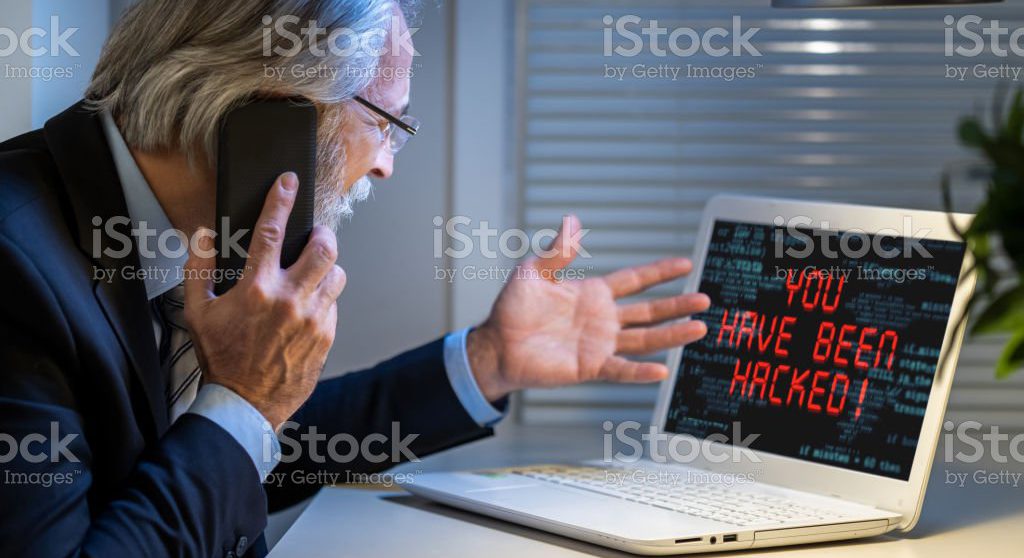 Sad businessman looking at computer monitor with inscription You have been hacked. Cybercrime concept.