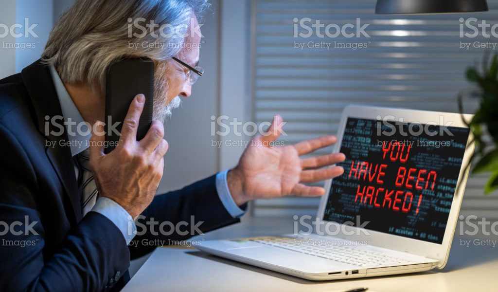 Sad businessman looking at computer monitor with inscription You have been hacked. Cybercrime concept.